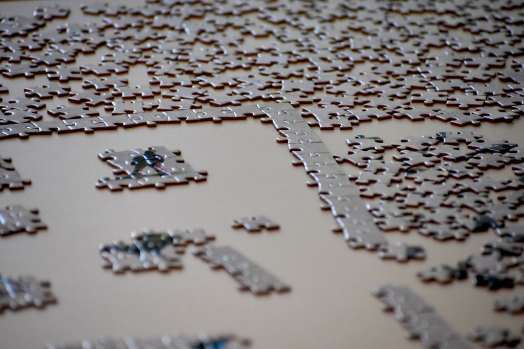 A detailed image of an incomplete jigsaw puzzle with pieces scattered on a table surface.