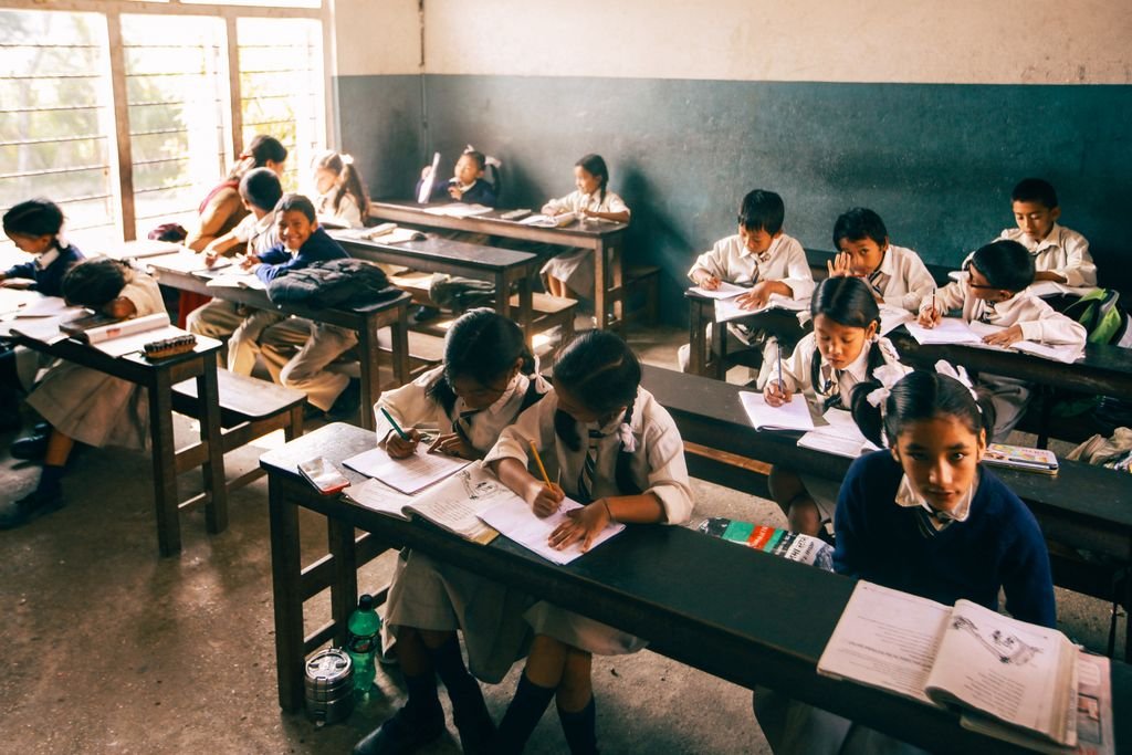 Elementary school children studying in a classroom, focusing intently on their work.