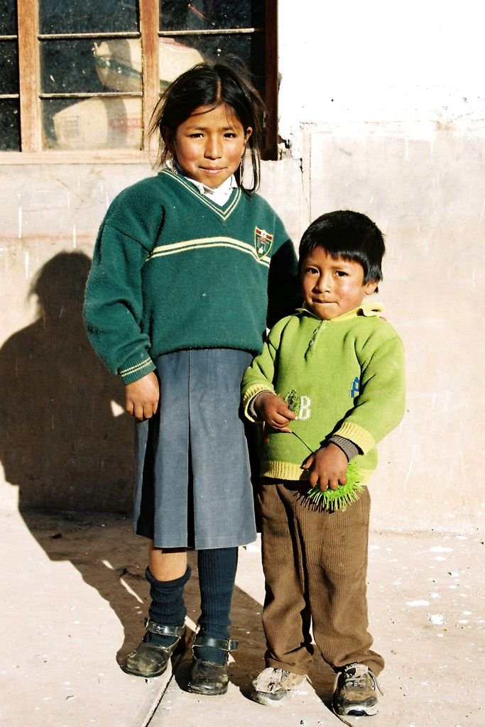 Two children stand in a sunny outdoor scene symbolizing traditional Peruvian life.